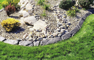 Closeup of a rock garden bed and lawn separated by landscape curbing